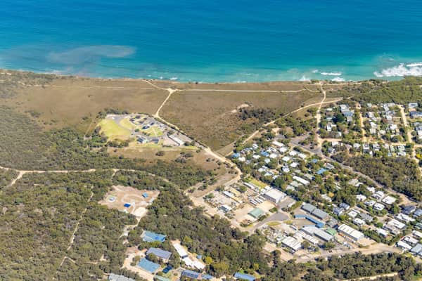 Aerial view of the Anglesea coastline in Victoria with blue ocean, coastal heathland, walking tracks and residential streets near Simmons Court.