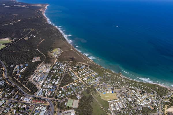 Aerial view of Anglesea coastline, residential streets, bushland reserves and ocean surf in Anglesea, Victoria.