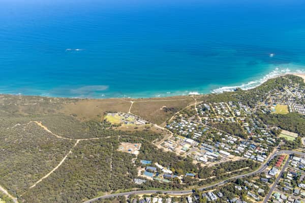 Aerial view of the Anglesea coastline with residential estates, coastal bushland, access tracks and blue ocean water in Anglesea, Victoria.