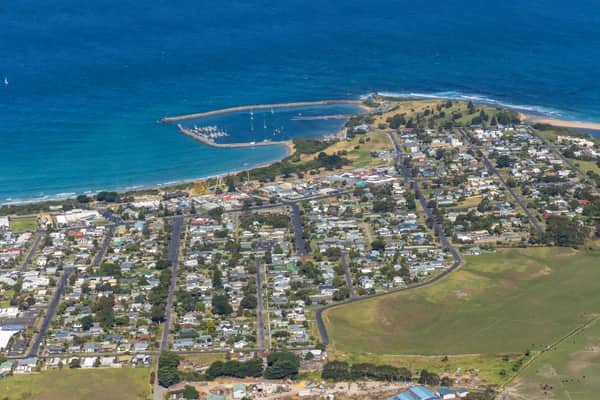 Aerial view of Apollo Bay Harbour, the coastline and surrounding township streets and homes in Apollo Bay, Victoria.