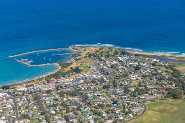 Aerial view of Apollo Bay Harbour, the marina breakwaters, residential streets and coastline at Apollo Bay on Victoria's Great Ocean Road.