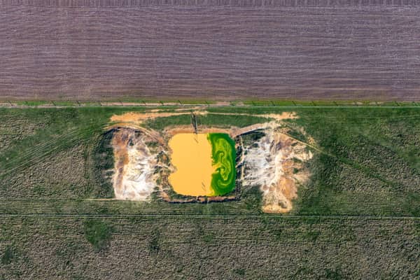 Aerial view of a small farm dam with green algae beside exposed earthworks and surrounding paddocks near Bannockburn, Victoria.