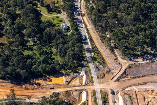 Aerial view of road construction along Gympie Connection Road in Victory Heights, Queensland, with earthworks, vehicles, bushland and nearby properties.