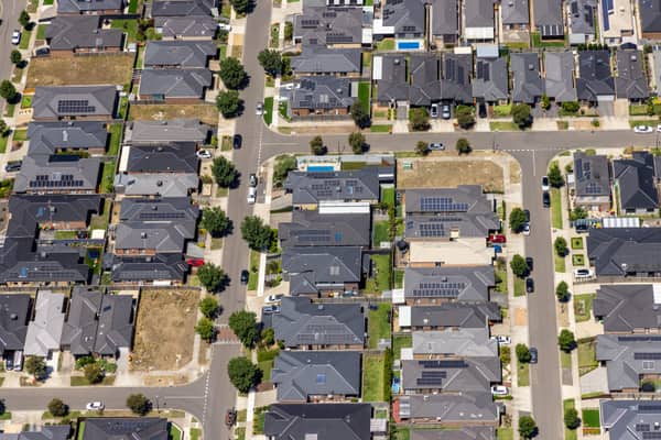 Aerial view of the Hollington Drive housing estate in Mickleham VIC, showing modern suburban homes, rooftop solar panels, residential streets, parked cars and vacant lots.