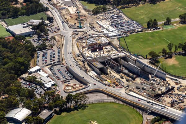 Aerial view of road and bridge construction beside sports fields, car parks and surrounding streets in Balwyn North, Victoria.