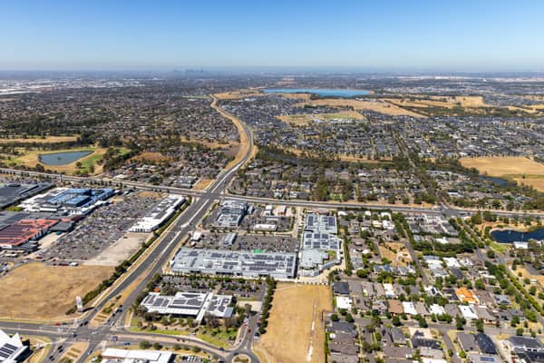 Aerial view of Craigieburn Road and Craigieburn Central in Craigieburn, showing the shopping centre, surrounding car parks, suburban streets, housing estates and distant Melbourne skyline.