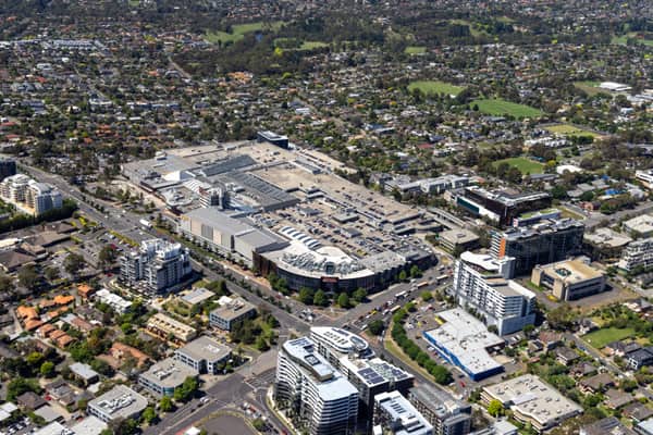Aerial view of Westfield Doncaster shopping centre with rooftop car parks, surrounding apartment buildings, Doncaster Road and suburban streets in Doncaster, Victoria.