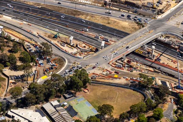 Aerial view of Bulleen Road crossing the Eastern Freeway in Balwyn North, with active road construction, traffic lanes, work zones, parked vehicles and surrounding trees.