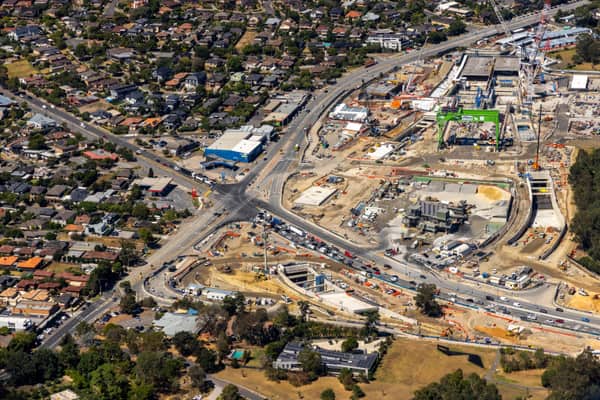Aerial view of North East Link construction in Heidelberg, showing major roadworks, excavation areas, site compounds, traffic and surrounding residential streets.