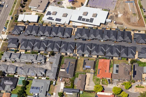 Aerial view of homes and townhouse rows near Marsh Crescent in Sunbury VIC, with rooftop solar panels, residential streets and nearby construction land visible.