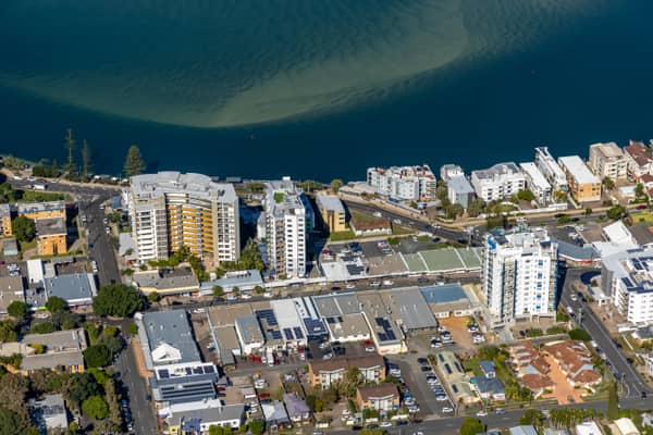 Aerial view of waterfront apartments and streets beside Pumicestone Passage in central Caloundra, Queensland.