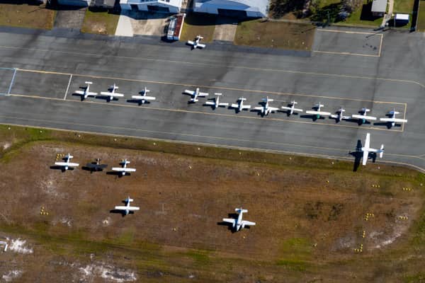 Aerial view of light aircraft parked on the apron and grass beside hangars at Caloundra Airport in Caloundra West, Queensland.